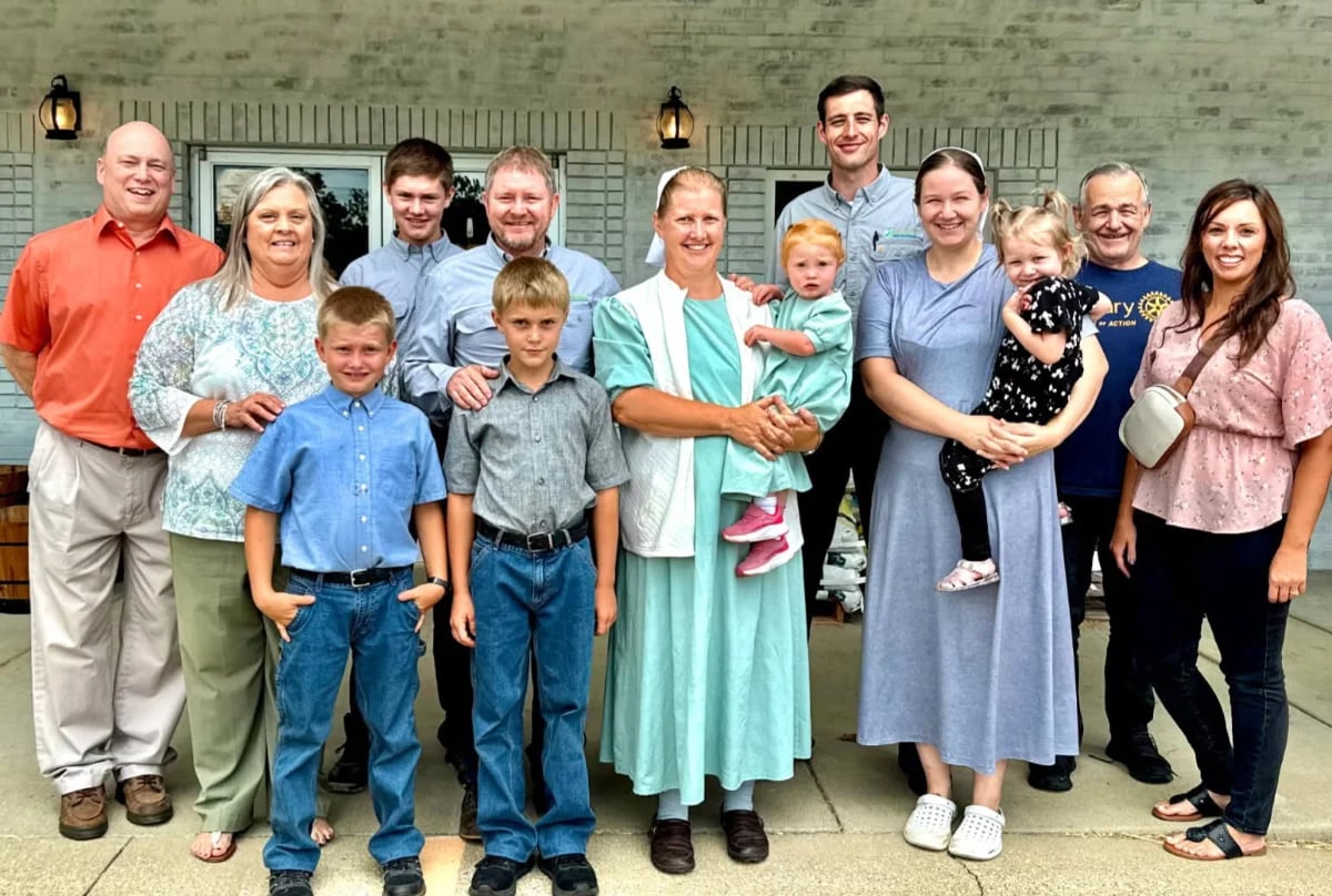 A multigenerational family group posing outside a brick building